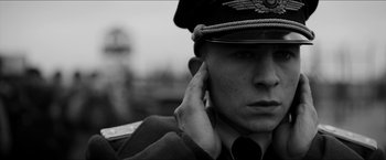 Movie still from “The Captain” (2017), directed by Robert Schwentke – A man in a military uniform is holding his hand to his ear; Close Up shot, Low angle