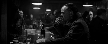 Movie still from “The Captain” (2017), directed by Robert Schwentke – A black and white photo of a man drinking a beer; Medium shot, Over the shoulder angle