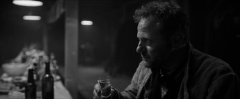 Movie still from “The Captain” (2017), directed by Robert Schwentke – A black and white photo of a man holding a glass of wine; Close Up shot, Over the shoulder angle