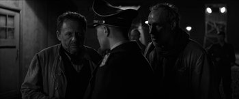 Movie still from “The Captain” (2017), directed by Robert Schwentke – A group of men standing next to each other in a dark room; Close Up shot, Over the shoulder angle