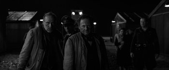 Movie still from “The Captain” (2017), directed by Robert Schwentke – A black and white photo of a group of people; Medium shot, Over the shoulder angle