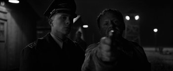Movie still from “The Captain” (2017), directed by Robert Schwentke – A man pointing a gun at a person in a uniform; Close Up shot, Over the shoulder angle