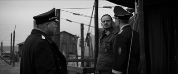 Movie still from “The Captain” (2017), directed by Robert Schwentke – A black - and - white photo of three men in uniform; Medium shot, Over the shoulder angle