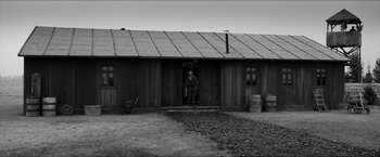 Movie still from “The Captain” (2017), directed by Robert Schwentke – A man standing in front of a building; Wide shot, Low angle