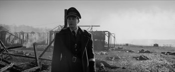 Movie still from “The Captain” (2017), directed by Robert Schwentke – A man in a military uniform standing in front of a destroyed building; Medium shot, Low angle