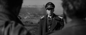 Movie still from “The Captain” (2017), directed by Robert Schwentke – A man in a military uniform is standing in a field; Medium shot, Over the shoulder angle