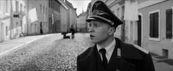 Movie still from “The Captain” (2017), directed by Robert Schwentke – A man in a military uniform standing on a cobblestone street; Close Up shot, High angle