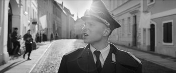 Movie still from “The Captain” (2017), directed by Robert Schwentke – A man wearing a uniform and a hat standing on a street; Medium shot, Low angle
