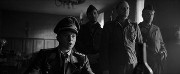 Movie still from “The Captain” (2017), directed by Robert Schwentke – A man in a military uniform with two other men in uniform; Medium shot, Over the shoulder angle