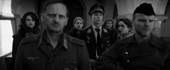 Movie still from “The Captain” (2017), directed by Robert Schwentke – A group of people standing next to each other wearing military uniforms; Medium shot, Over the shoulder angle