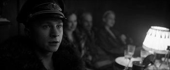 Movie still from “The Captain” (2017), directed by Robert Schwentke – A group of people sitting next to each other in a dark room; Close Up shot, Over the shoulder angle