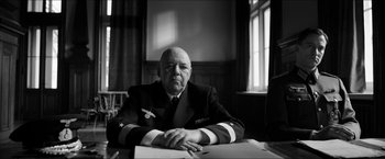 Movie still from “The Captain” (2017), directed by Robert Schwentke – An older man sitting at a table in front of a window; Medium shot, Low angle