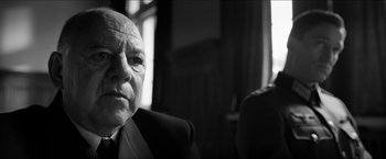 Movie still from “The Captain” (2017), directed by Robert Schwentke – An older man wearing a suit and tie in front of a window; Close Up shot, Low angle