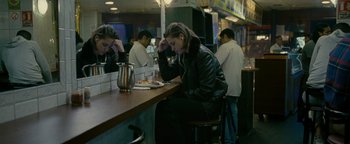 Movie still from “Personal Shopper” (2016), directed by Olivier Assayas – A woman sitting at a table in front of a plate of food; Medium shot, High angle