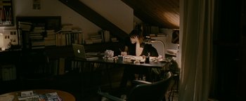 Movie still from “Personal Shopper” (2016), directed by Olivier Assayas – A woman sitting at a table with a laptop; Wide shot, High angle