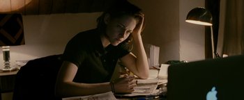 Movie still from “Personal Shopper” (2016), directed by Olivier Assayas – A woman sitting at a table with papers in front of her; Medium shot, High angle