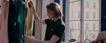 Movie still from “Personal Shopper” (2016), directed by Olivier Assayas – A woman in a black shirt is holding a sweater; Medium shot, Over the shoulder angle