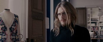 Movie still from “Personal Shopper” (2016), directed by Olivier Assayas – A man with long blonde hair wearing glasses and a black sweater; Close Up shot, Over the shoulder angle