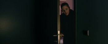 Movie still from “Personal Shopper” (2016), directed by Olivier Assayas – A woman standing in front of an open door; Medium shot, Over the shoulder angle