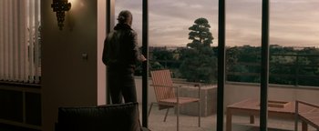 Movie still from “Personal Shopper” (2016), directed by Olivier Assayas – A man standing in front of an open sliding glass door; Wide shot, Over the shoulder angle