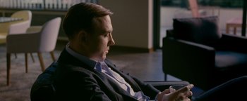 Movie still from “Personal Shopper” (2016), directed by Olivier Assayas – A man sitting on a couch with a cup in his hand; Medium shot, High angle