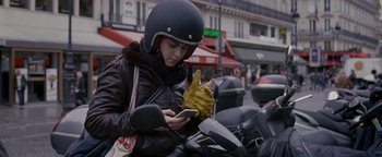 Movie still from “Personal Shopper” (2016), directed by Olivier Assayas – A person on a motorcycle looking at a cell phone; Medium shot, Low angle