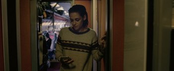 Movie still from “Personal Shopper” (2016), directed by Olivier Assayas – A person standing in a room holding a cell phone; Medium shot, Low angle