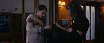 Movie still from “Personal Shopper” (2016), directed by Olivier Assayas – Two women looking at something in a black bag; Medium shot, High angle