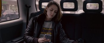 Movie still from “Personal Shopper” (2016), directed by Olivier Assayas – A woman sitting in a car looking at her cell phone; Medium shot, Over the shoulder angle