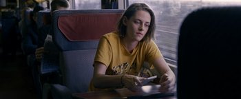 Movie still from “Personal Shopper” (2016), directed by Olivier Assayas – A woman sitting at a table looking at her phone; Medium shot, High angle