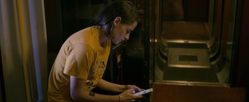 Movie still from “Personal Shopper” (2016), directed by Olivier Assayas – A woman sitting on a chair looking at a cell phone; Medium shot, High angle