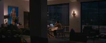 Movie still from “Personal Shopper” (2016), directed by Olivier Assayas – A person sitting at a table with a laptop in front of a window; Wide shot, High angle