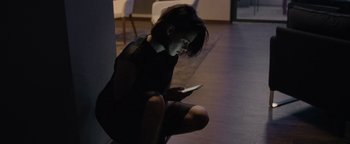 Movie still from “Personal Shopper” (2016), directed by Olivier Assayas – A woman sitting on the ground looking at a cell phone; Medium shot, High angle