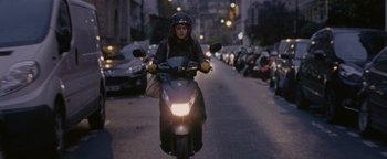 Movie still from “Personal Shopper” (2016), directed by Olivier Assayas – A person riding a motorcycle down a street at night; Wide shot, High angle