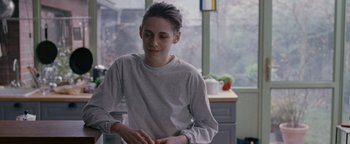 Movie still from “Personal Shopper” (2016), directed by Olivier Assayas – A young man in a white t - shirt in front of a window; Medium shot, Over the shoulder angle