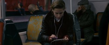 Movie still from “Personal Shopper” (2016), directed by Olivier Assayas – A woman sitting on a bench looking at a tablet; Medium shot, Over the shoulder angle