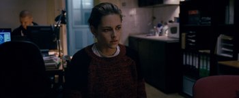 Movie still from “Personal Shopper” (2016), directed by Olivier Assayas – A woman in a sweater is standing in a kitchen; Medium shot, Over the shoulder angle