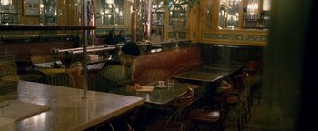 Movie still from “Personal Shopper” (2016), directed by Olivier Assayas – A person sitting at a table in a restaurant; Wide shot, High angle