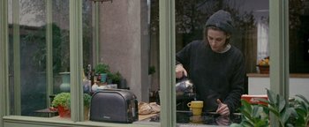 Movie still from “Personal Shopper” (2016), directed by Olivier Assayas – A person pouring a cup of coffee into a mug; Medium shot, High angle