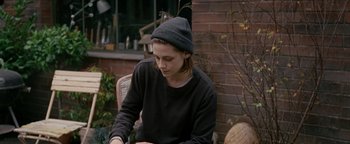 Movie still from “Personal Shopper” (2016), directed by Olivier Assayas – A person sitting in a chair with a hat on; Medium shot, Over the shoulder angle