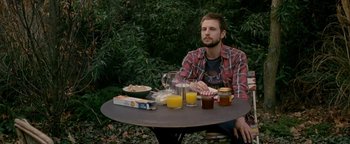 Movie still from “Personal Shopper” (2016), directed by Olivier Assayas – A man sitting at a table with food on it; Medium shot, High angle