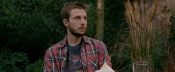 Movie still from “Personal Shopper” (2016), directed by Olivier Assayas – A man in a plaid shirt holding a book; Close Up shot, Over the shoulder angle