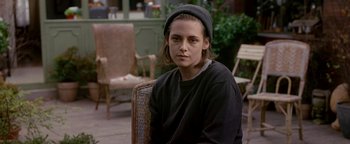 Movie still from “Personal Shopper” (2016), directed by Olivier Assayas – A person sitting on a chair wearing a hat; Close Up shot, Over the shoulder angle