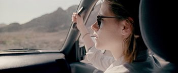 Movie still from “Personal Shopper” (2016), directed by Olivier Assayas – A woman driving in a car on a road; Close Up shot, Over the shoulder angle