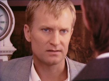 Movie still from “The Celebration” (1998), directed by Thomas Vinterberg – A person wearing a suit and tie; Close Up shot, Over the shoulder angle