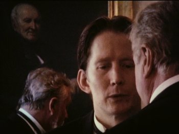Movie still from “The Celebration” (1998), directed by Thomas Vinterberg – A man in a suit and tie standing in front of another man; Close Up shot, Over the shoulder angle