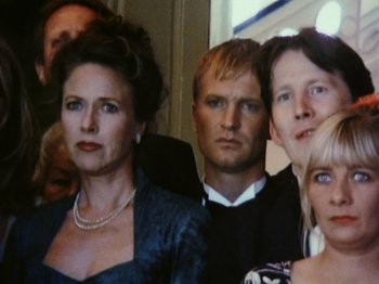 Movie still from “The Celebration” (1998), directed by Thomas Vinterberg – A group of people standing next to each other in a room; Close Up shot, Low angle