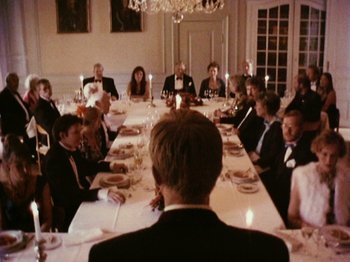 Movie still from “The Celebration” (1998), directed by Thomas Vinterberg – A group of people sitting around a long dinner table; Wide shot, High angle