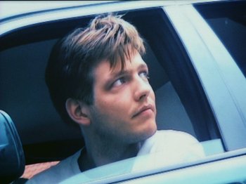 Movie still from “The Celebration” (1998), directed by Thomas Vinterberg – A man sitting in the driver's seat of a car looking out of the window; Close Up shot, Low angle