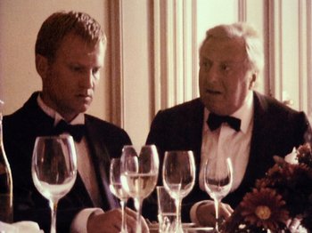 Movie still from “The Celebration” (1998), directed by Thomas Vinterberg – Two men in tuxedos sitting at a dinner table; Close Up shot, Over the shoulder angle